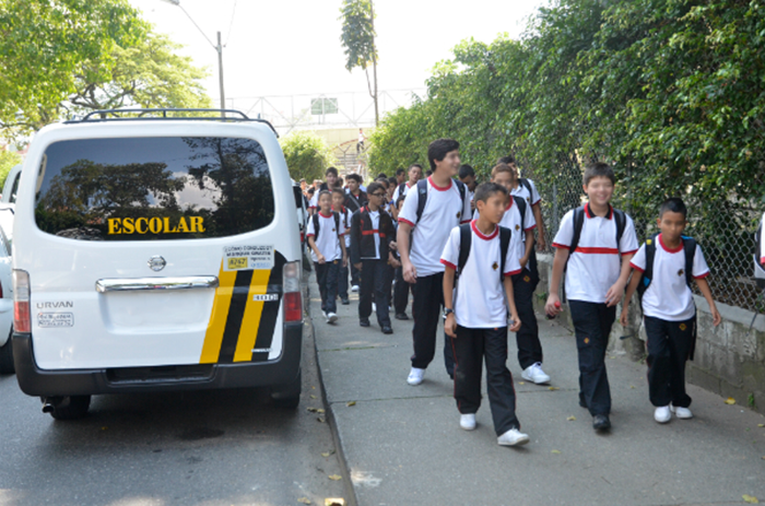 Estudiantes junto a un vehículo de transporte escolar.